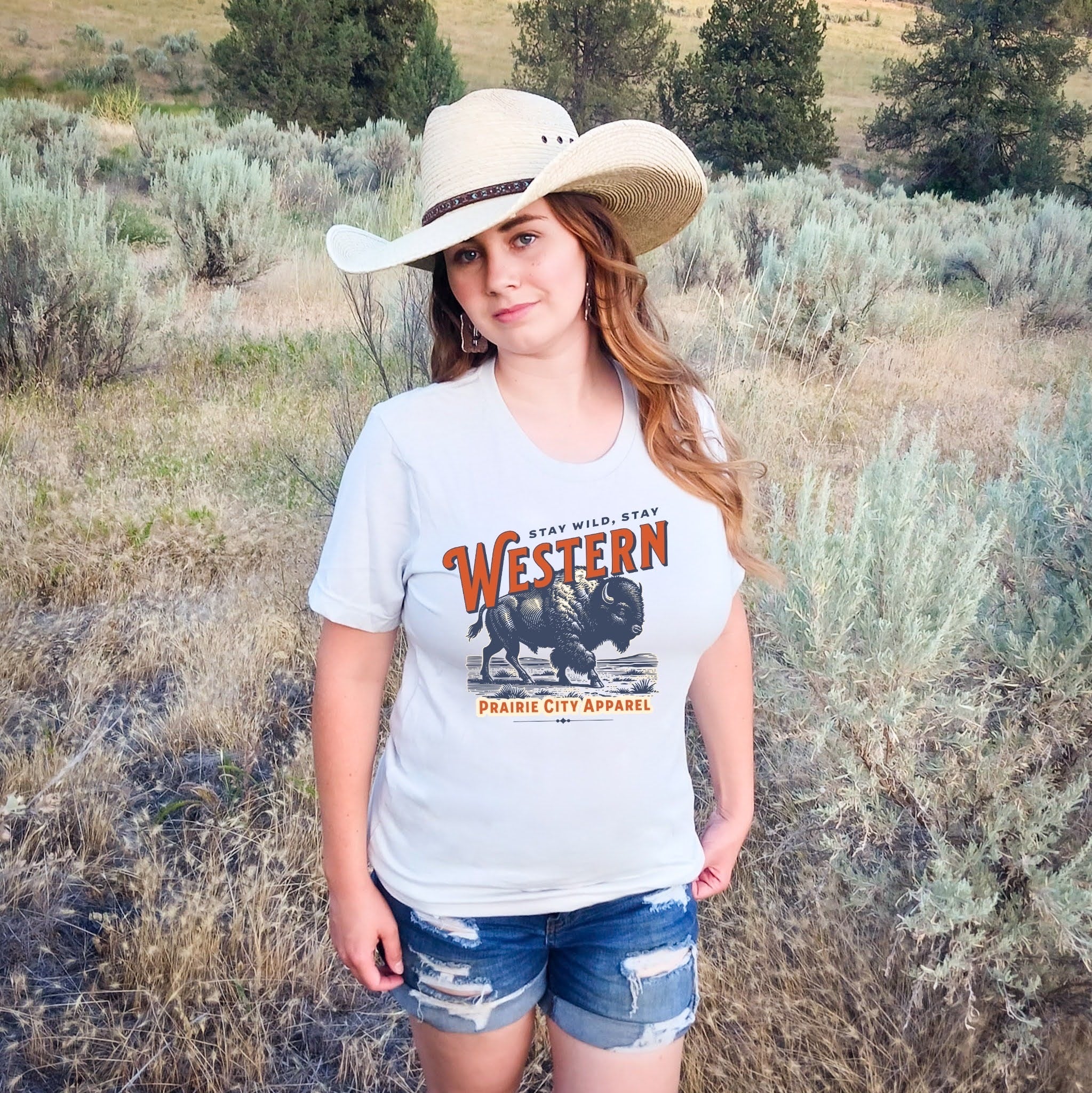 Person wearing a 'Western' t-shirt and cowboy hat in a natural setting