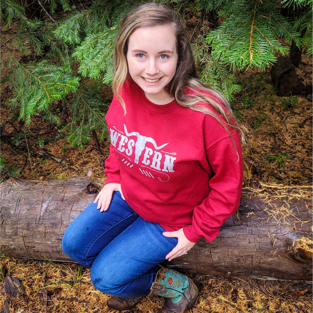 Women in red  Wester cowgirl crewneck sitting on a log in a forest 